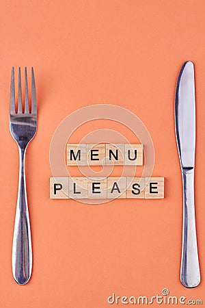 The inscription Menu please on wooden cubes with cutlery on color background. Stock Photo