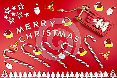 The Inscription Merry Christmas made of wooden letters, lying flat from above, isolated on a red background. Visible candy canes, Stock Photo