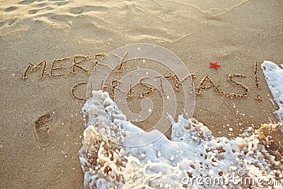 The inscription Merry Christmas on the sand on the beach. Stock Photo