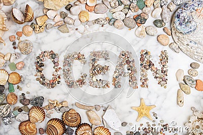 Inscription ocean with pebbles, star, stones and shells lying on a marble background, composition of ocean stones and seashells, w Stock Photo