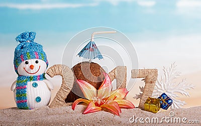 The inscription 2017 in sand, snowman, Christmas ball on the background of the ocean Stock Photo