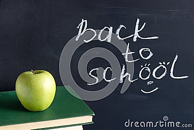 Inscription text Back to school on black chalkboard and green Apple on stack books textbooks, Concept education Stock Photo