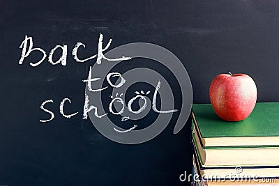 Inscription text Back to school on black chalkboard and red apple on stack books textbooks, Concept education Stock Photo