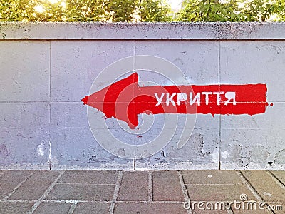 The inscription in Ukrainian SHELTER on the wall. Signpost direction to the bomb shelter in Ukrainian. Bomb shelter sign on the Editorial Stock Photo