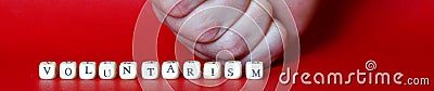 The inscription voluntarism and a fragment of a clenched male fist on a red background. The concept of philosophical understanding Stock Photo