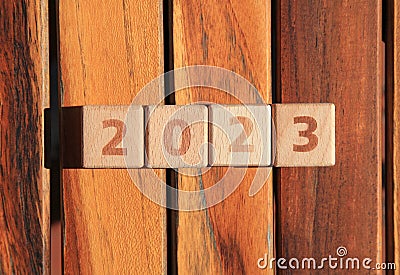 Inscription 2023. Wooden square cubes and numbers on brown wooden surface means coming New Year Eve Stock Photo