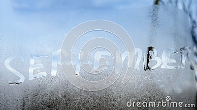 the inscription of the word September with a heart on a texture with condensation on the glass, a reaction to a sudden Stock Photo