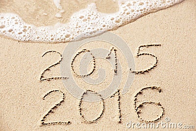 2015 2016 inscription written in the wet yellow beach sand being Stock Photo