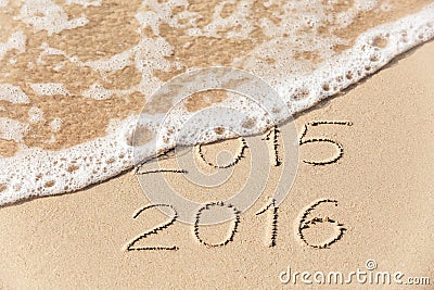 2015 2016 inscription written in the wet yellow beach sand being Stock Photo