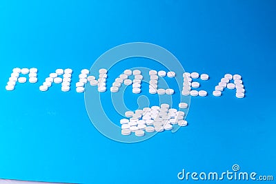 The inscription "Panacea" made of pills on a blue background Stock Photo