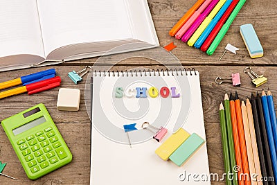 inscription of & x22;school& x22;, book, calculator, notepad and other stationery on brown wooden table Stock Photo