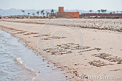 Inscriptions on the sand with sea waves Stock Photo