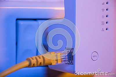 Insert ethernet cable into WiFi extender device which is in electrical socket on the wall Stock Photo