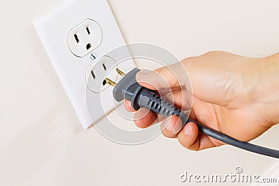 Inserting Power Cord Receptacle in wall outlet Stock Photo