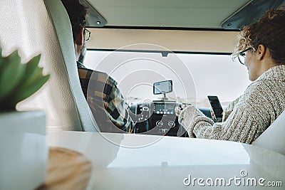 Inside back view of vehicle cabin like motorhome and couple traveling and using gps navigation system and phone to plan road trip Stock Photo