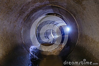 Inside dark round underground urban sewer tunnel Stock Photo