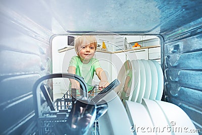 Inside dishwasher little blond toddler take dishes Stock Photo