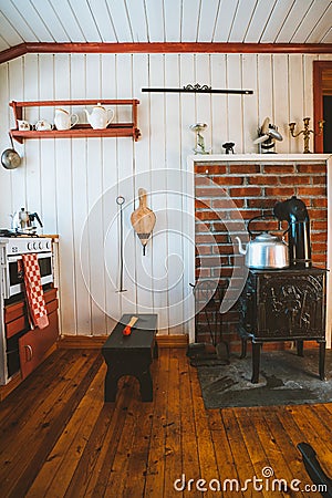 Inside shot of a cozy house with a teapot on the wood oven next to a small chair in the kitchen Stock Photo