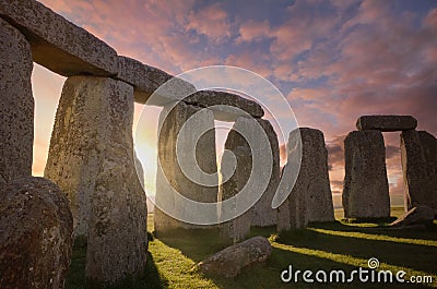 Inside the Stonehenge Circle of Stones with a Dramatic Sky Sunrise behind it Stock Photo