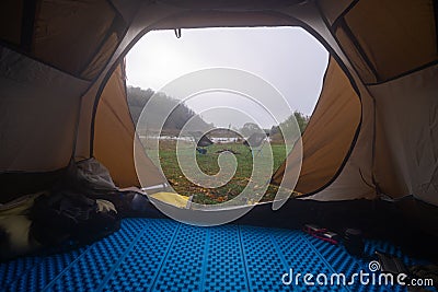 Inside the tourist tent, first person view. Foggy morning near the river. Folding chair and table. Tourism and hobby Stock Photo