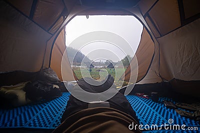 Inside the tourist tent, first person view. Foggy morning near the river. Folding chair and table. Tourism and hobby. Man legs Stock Photo
