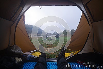 Inside the tourist tent, first person view. Foggy morning near the river. Folding chair and table. Tourism and hobby. Man legs Stock Photo