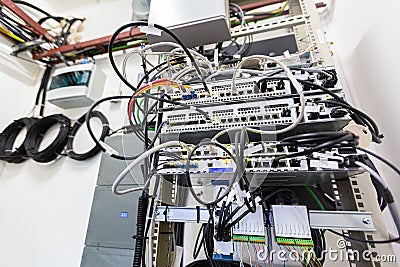 Inside of typical modern basic station of communications equipment and bights of optic cables or fibers on the wall Stock Photo