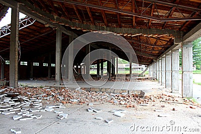 Inside of wide large hangar building with missing destroyed red brick support walls and unusual bent roof at abandoned military Stock Photo