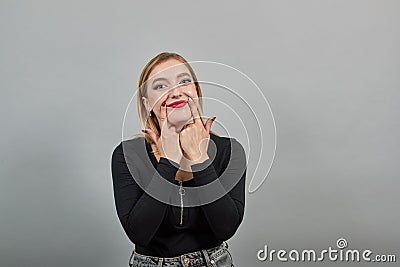 Insincere woman shows a fake smile, pulls the skates of lips with index fingers Stock Photo