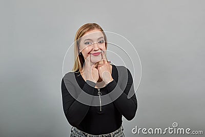 Insincere woman shows fake smile, stretches the tips of mouth with index fingers Stock Photo