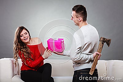 Insincire man holding axe giving gift box to woman Stock Photo