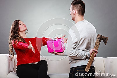 Insincire man holding axe giving gift box to woman Stock Photo