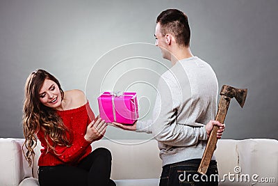 Insincire man holding axe giving gift box to woman Stock Photo