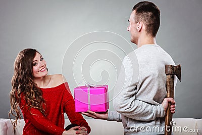 Insincire man holding axe giving gift box to woman Stock Photo