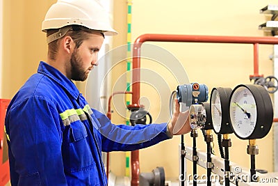 Inspector checking pressure gauges on heating boiler system Stock Photo