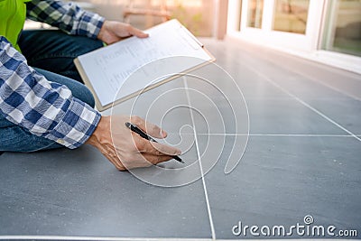 inspector or engineer is inspecting construction check tiled floor. Engineers and architects or contactor count materials for Stock Photo