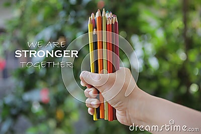 Inspiratinal motivational quote - We are stronger together. With young woman hand holds bunch of pencil colored and blurry green. Stock Photo