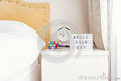 Inspiration Motivational Life Quotes hashtag Rule your day message on lightened box with alarm clock, notebooks and rubik`s cube Editorial Stock Photo