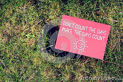 Inspirational message of Don`t Count The Days, Make The Days Count on paper on grass in nature. Being productive and making most Stock Photo
