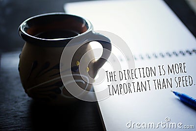Inspirational motivational quote - The direction is more important than speed. Text message on paper book with a cup of coffee. Stock Photo