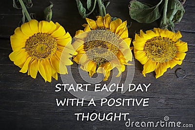 Inspirational motivational quote - Start each day with a positive thought. With yellow sun flowers on rustic wooden table Stock Photo