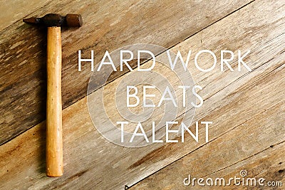 Inspirational and motivational quotes.Hard work beats talent. Hammer on wooden background Stock Photo