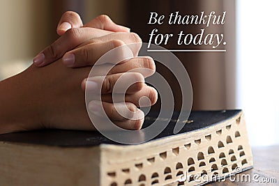 Inspirational quote - Be thankful for today. With background of young woman clenched prayer hands on a bible book. Stock Photo