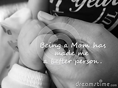 Inspirational quote- Being a Mom has made me a better person. With blurry image of a fragile little baby new born hand and fingers Stock Photo