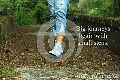 Inspirational quote- Big journeys begin with small steps. With feet of young woman walking surrounding with fresh green nature Stock Photo