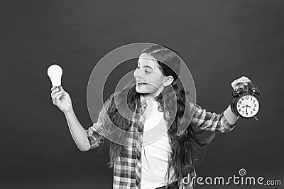 Inspired child hold clock red background. Inspiration and brainstorming. Electricity energy. Little girl hold light bulb Stock Photo