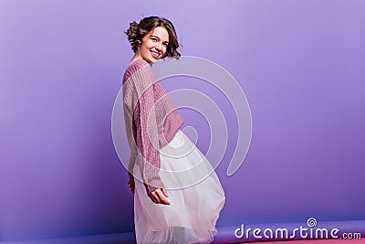 Inspired woman in funny winter hat waving hands on purple background. Indoor photo of winsome brunette girl in lush Stock Photo