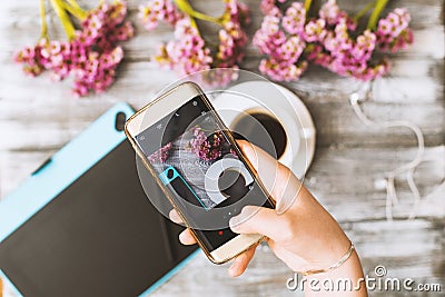 Instagram photographer blogging workshop concept, hand holding phone and taking photo of stylish flowers, cup of coffee Stock Photo