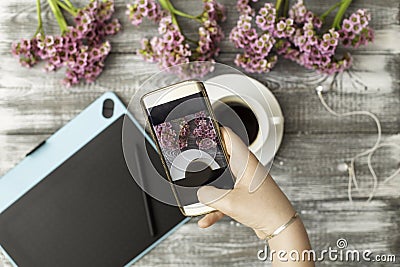 Instagram photographer blogging workshop concept, hand holding phone and taking photo of stylish flowers, cup of coffee Stock Photo