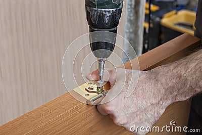 Install door hinges, carpenter tightening screws using screwdri Stock Photo